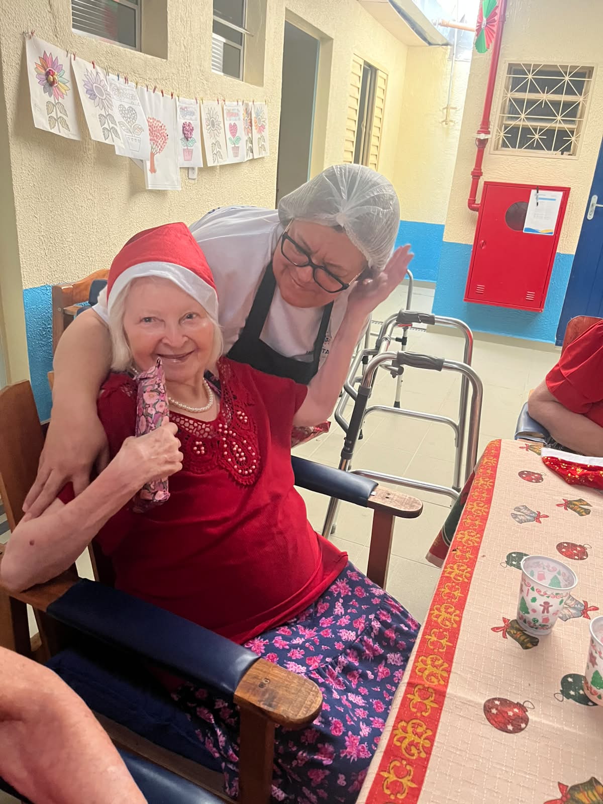 Idosa em momento de Natal com cuidadora no Incantare Residencial Sênior
